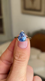 Close-up video of a vintage inspired pear-cut bluebell sapphire solitaire engagement ring, highlighting the brilliance, faceting and delicate yellow gold solitaire setting.