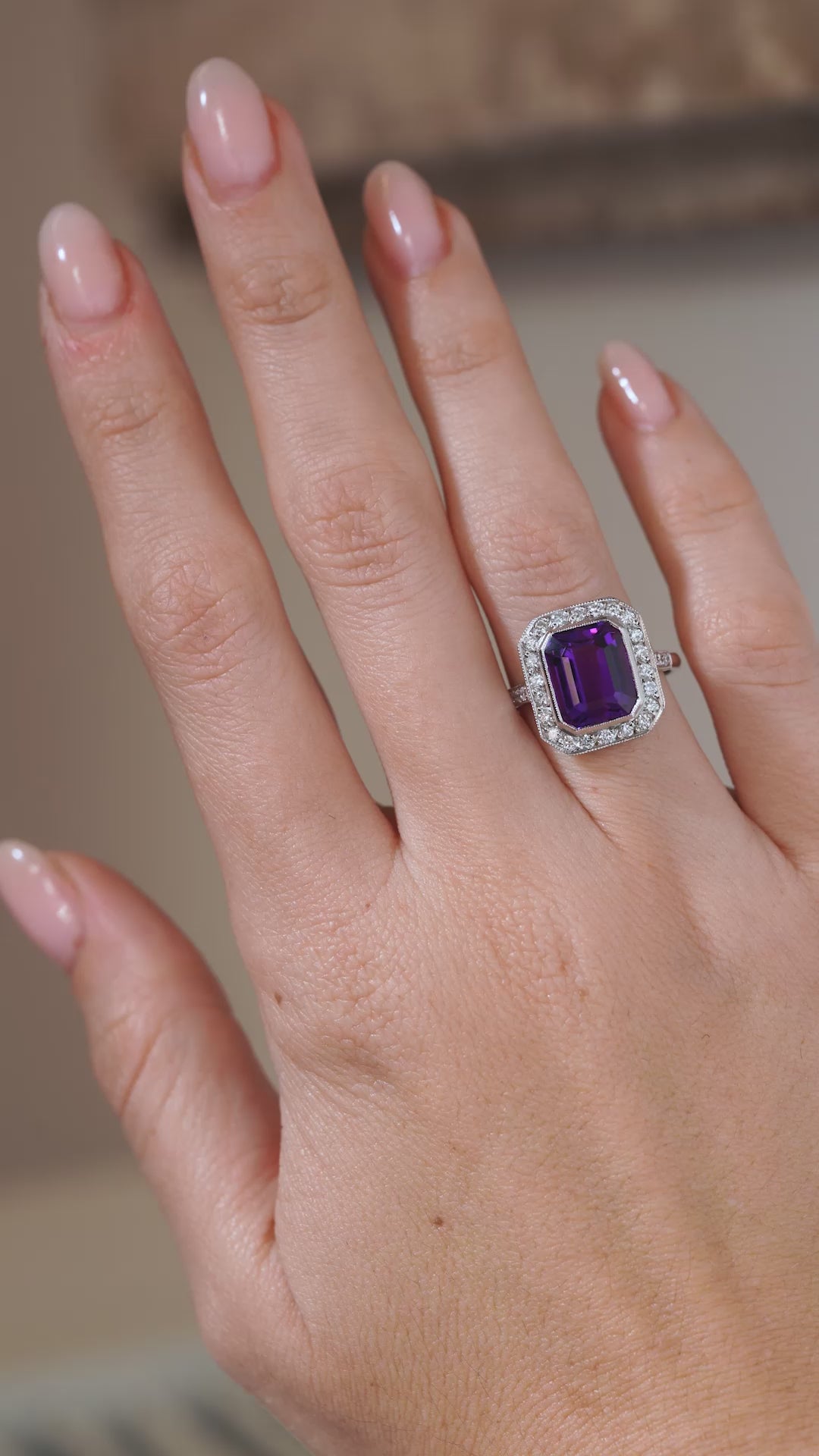 A video of an antique Art Deco amethyst and diamond cluster ring modelled on a hand, highlighting the rich purple amethyst, geometric diamond halo and intricate white gold setting.