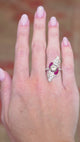 Art Nouveau cocktail ring worn on hand showing curved form and ruby accents.
