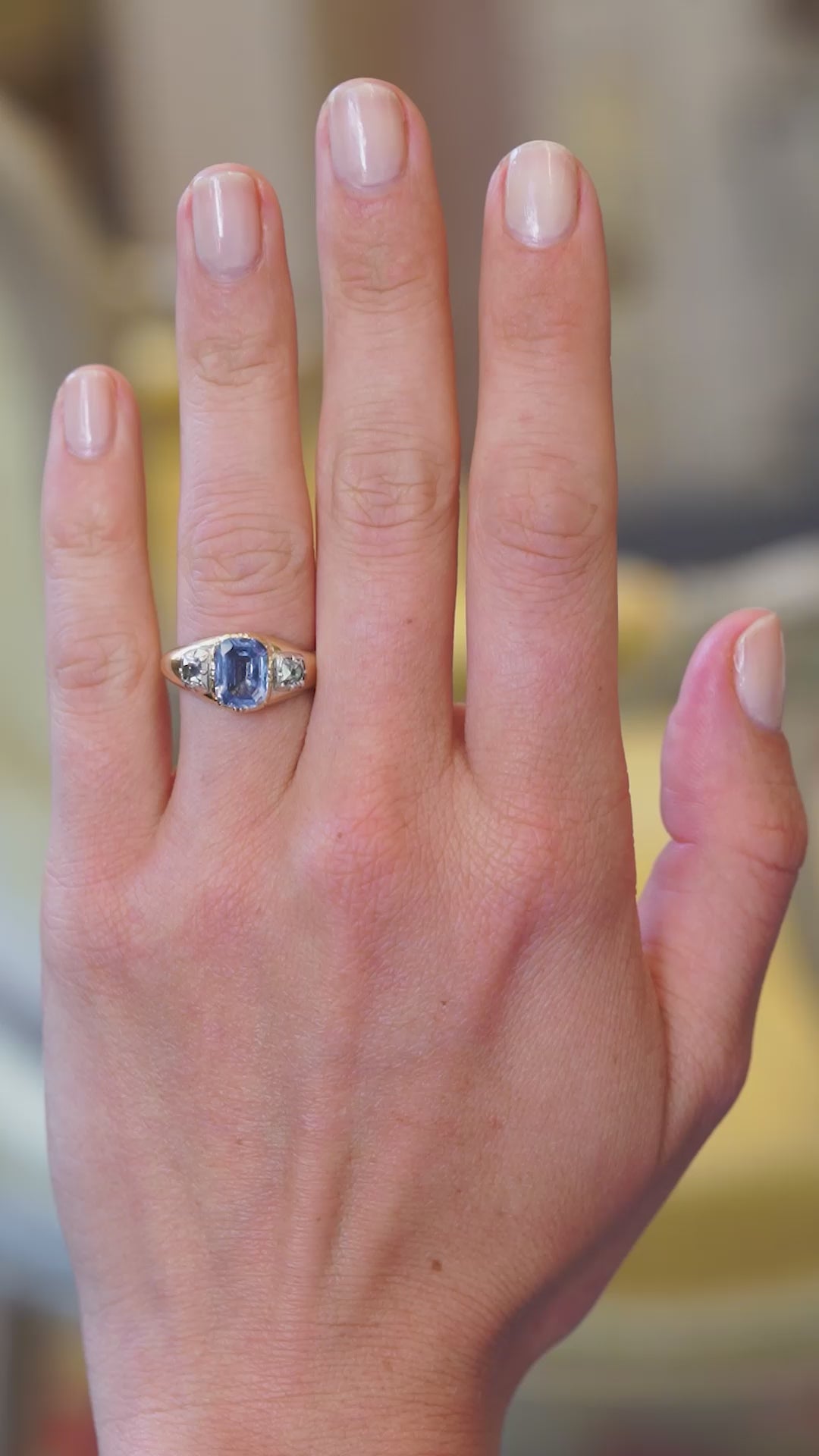 Sapphire and diamond three stone ring worn on hand showing soft blue tone and natural movement.