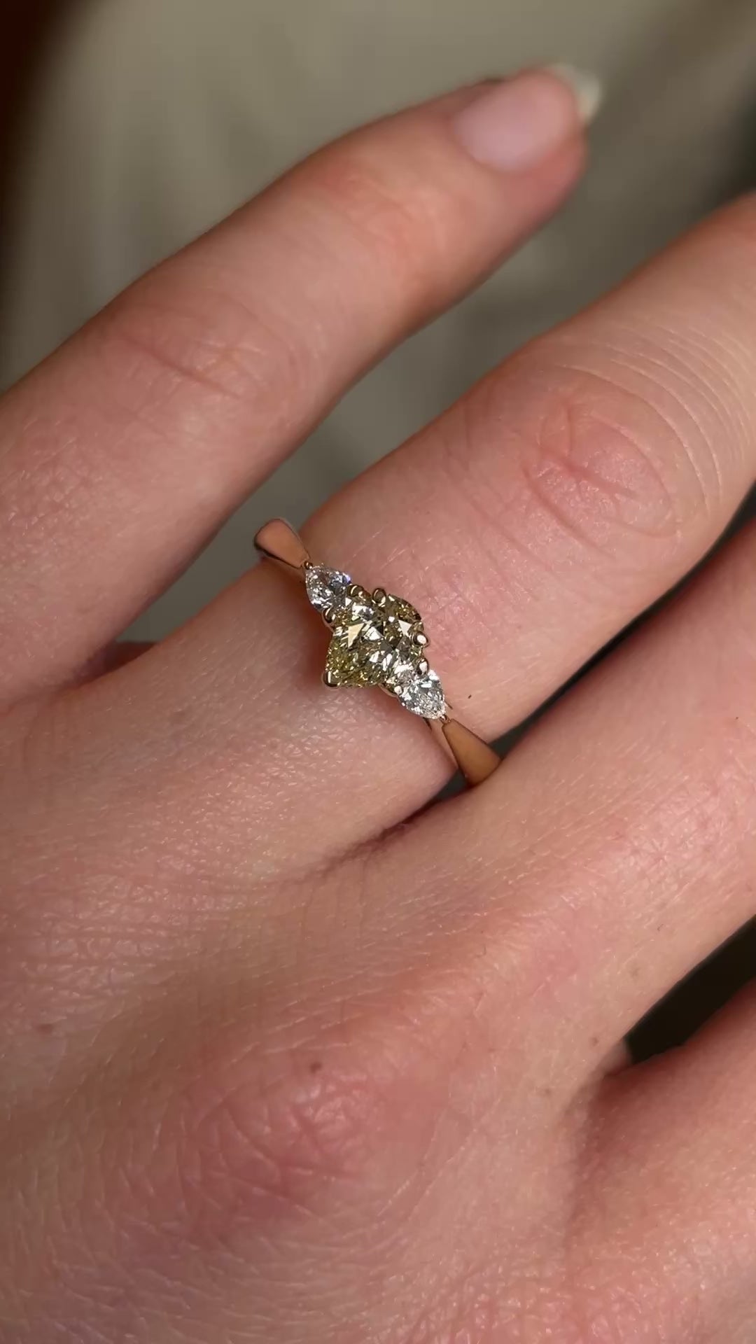 Pear-cut diamond three-stone engagement ring worn on hand at a distance to show diamond clarity and scale. 