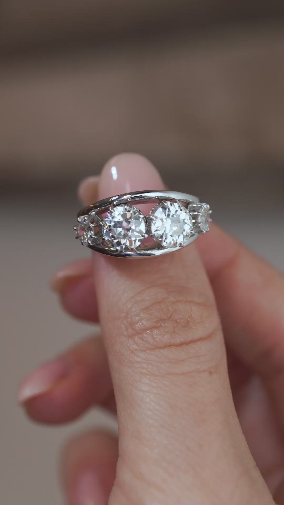 A close-up video of the vintage diamond ring held between fingers, showcasing the brilliant diamonds and intricate platinum detailing.