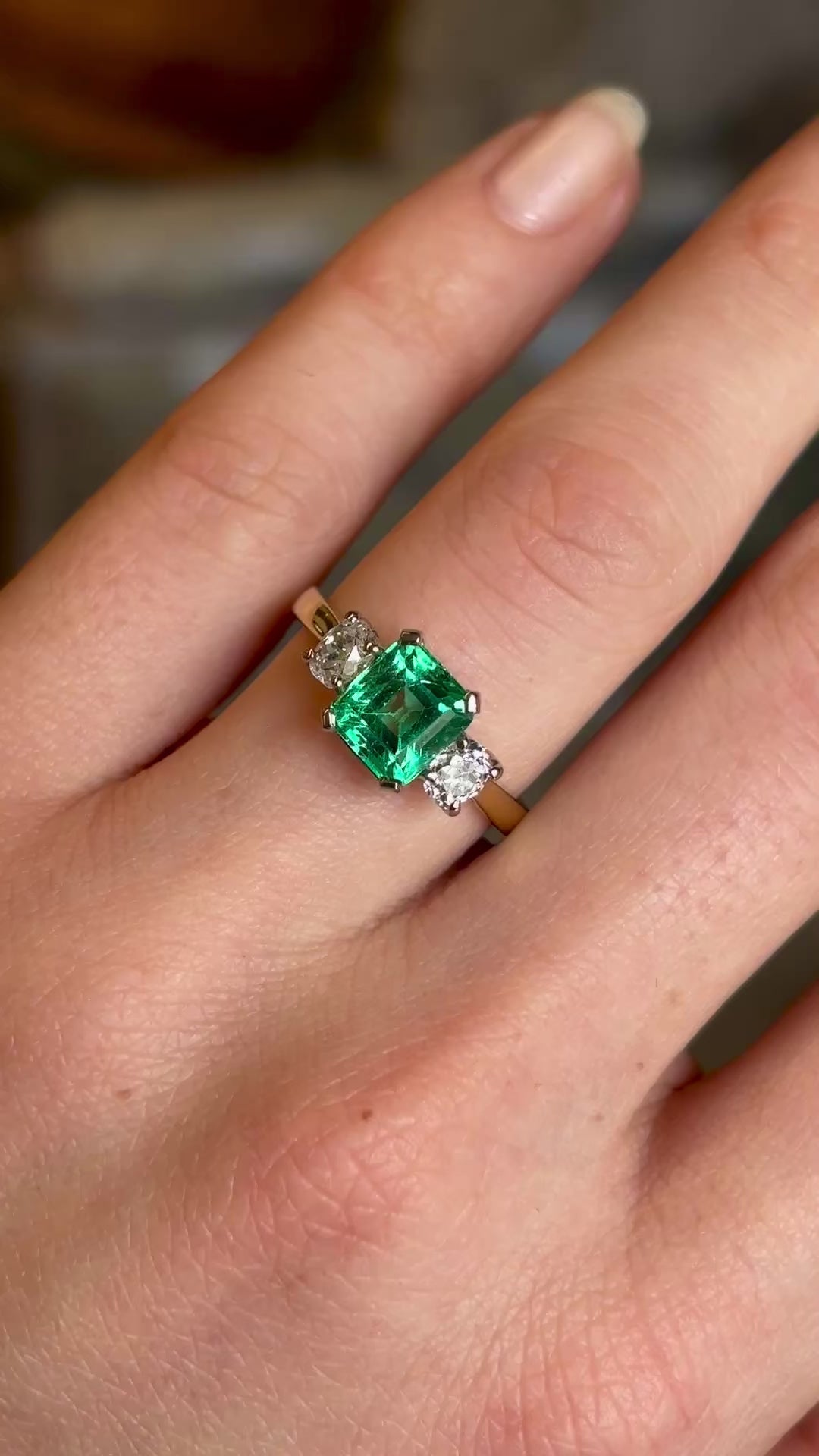 Vintage, emerald and diamond three-stone engagement ring worn on hand and moved slowly to show details. 