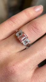 Lab-pink diamond and white diamond three-stone ring worn on hand in motion, illustrating brilliance and presence when worn.