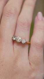 A video of a vintage three-stone diamond engagement ring worn on the hand.