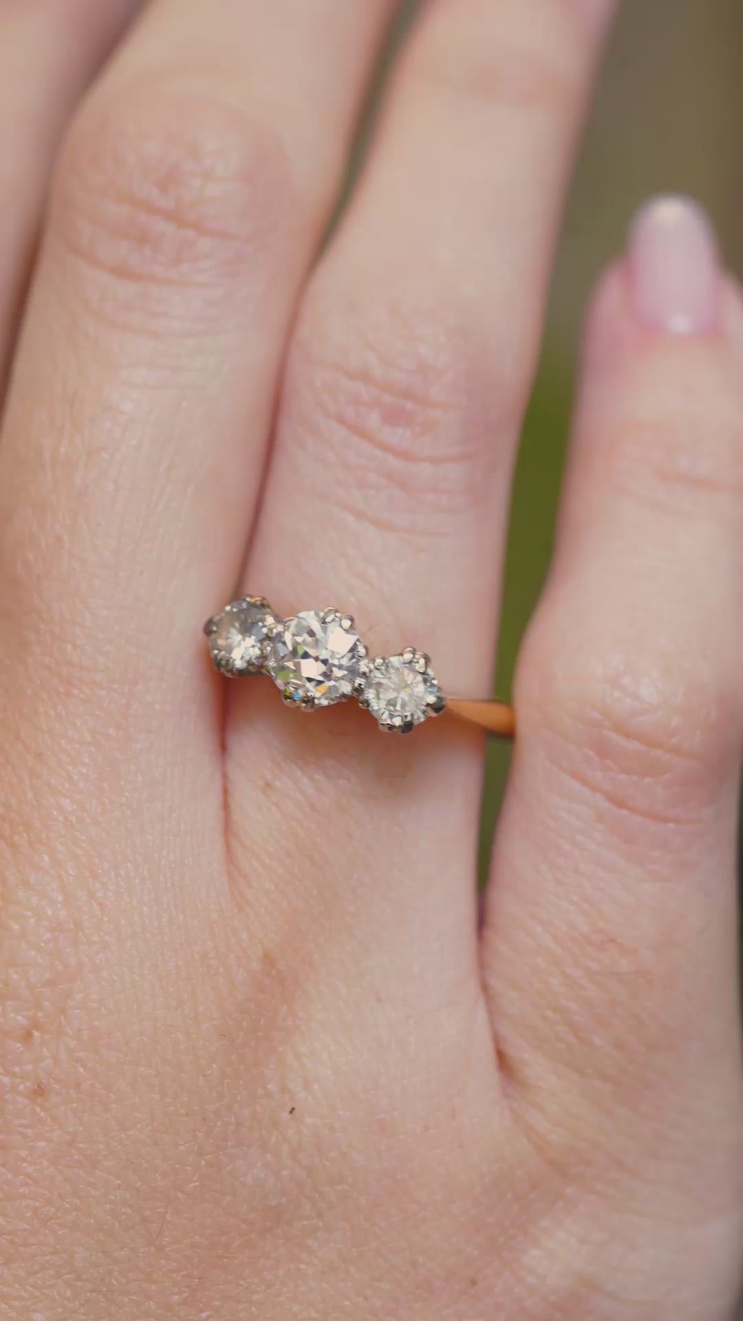 A video of a vintage three-stone diamond engagement ring worn on the hand.