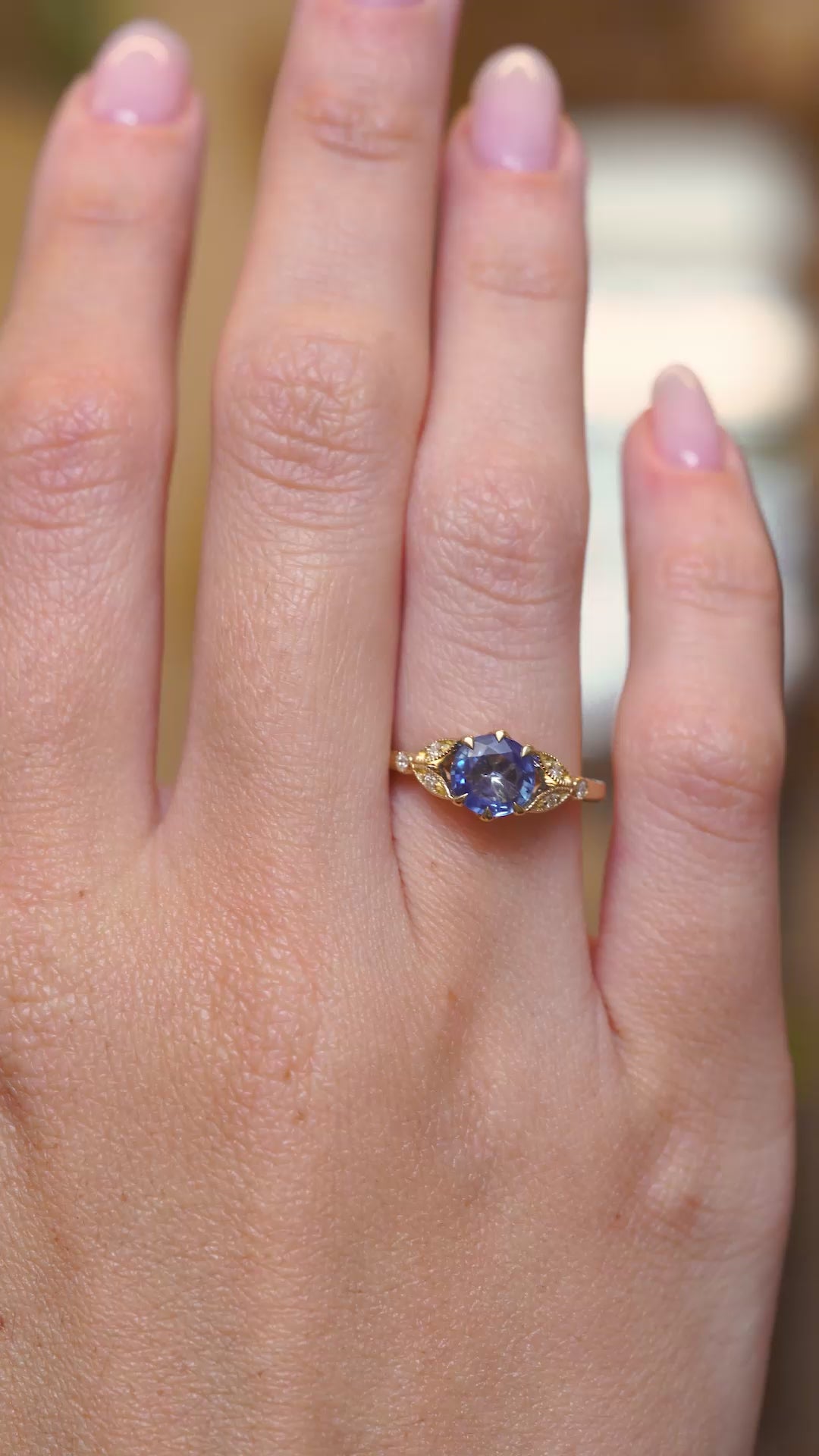 A video of a Blue-purple sapphire and diamond engagement ring showcased on the hand in a vintage-inspired yellow gold setting.