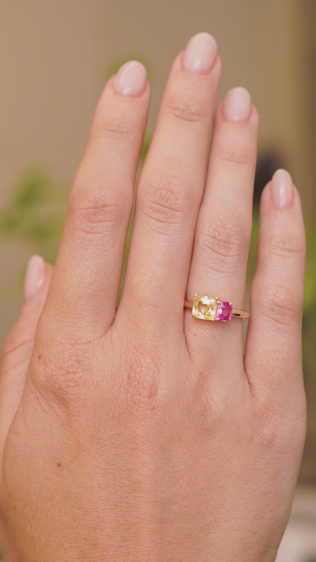 a video of an Antique-inspired, Yellow and pink sapphire Toi et Moi engagement ring in yellow gold worn on the hand and held at a distance to show scale
