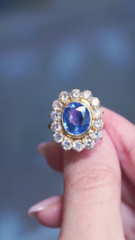 Vintage French sapphire and diamond cluster ring showing a vivid blue centre stone and sparkling diamonds in motion between fingers.