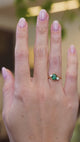 Emerald and diamond three stone ring worn on hand showing rich green tone and natural movement.