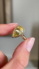Detailed video of a large pear-cut Sri Lankan yellow sapphire set in yellow gold, held between fingers to showcase the smooth rub-over setting, vibrant colour and elegant antique-inspired design against a vintage interior background.