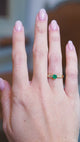 Five stone emerald and diamond ring worn on hand with natural light.