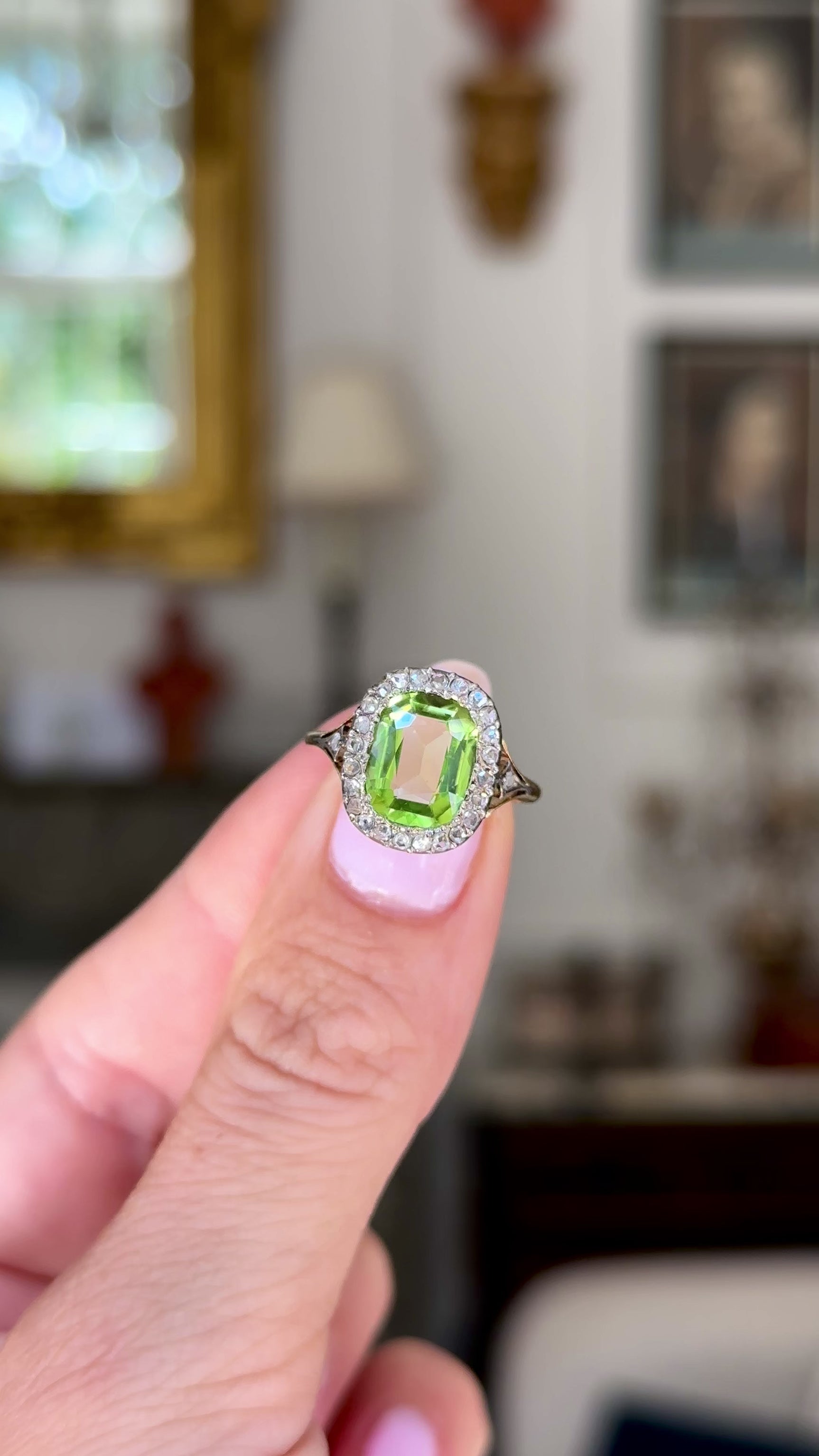 antique peridot and diamond ring, held in fingers and rotated to give perspective, front view.