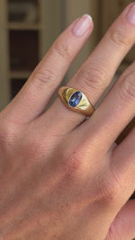 Antique Edwardian iris-blue sapphire gypsy engagement ring featuring an iris-blue sapphire in a traditional gold gypsy setting, displayed on a hand.