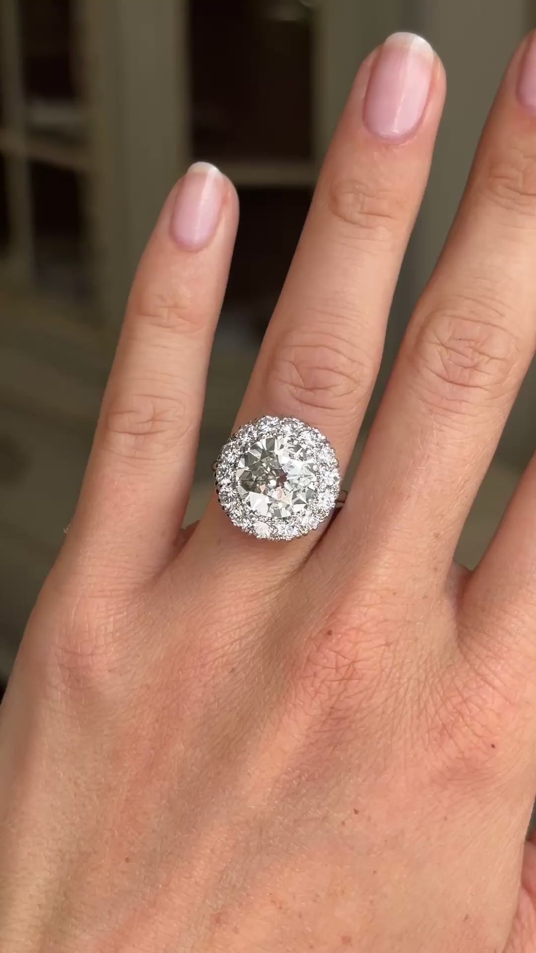 Vintage 1950s platinum diamond cluster engagement ring worn on hand, featuring approximately 4 carats of brilliant diamonds, filmed against a softly lit vintage interior backdrop to showcase exceptional sparkle and presence.