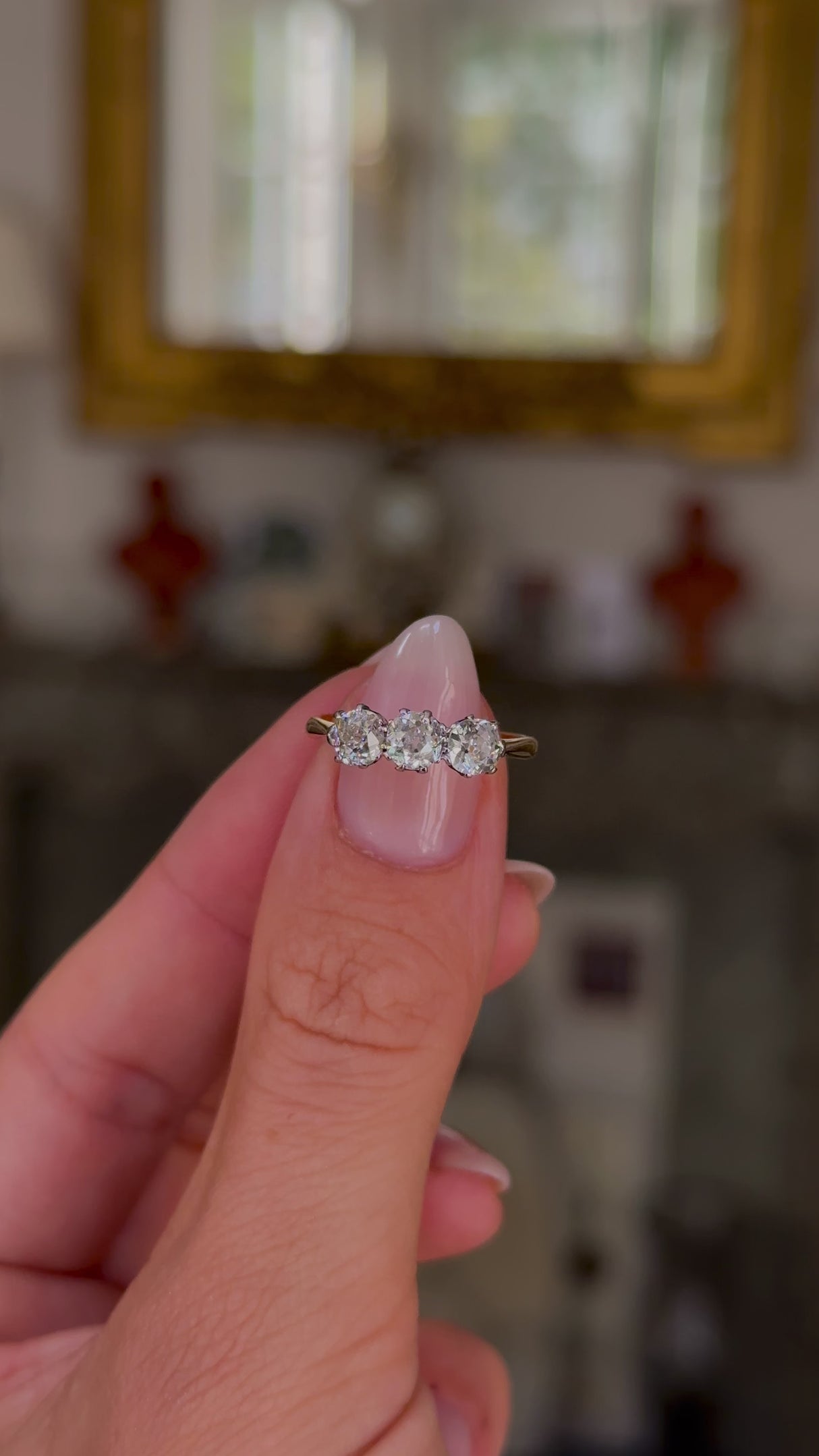 antique three stone diamond engagement ring, 18ct yellow gold band, held in fingers and rotated to give perspective, front view. 