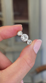 Antique Edwardian old-cut diamond three-stone engagement ring featuring three old-cut diamonds in a timeless trilogy design, held by hand for detailed viewing.