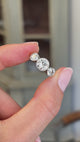 Antique Edwardian old-cut diamond three-stone engagement ring featuring three old-cut diamonds in a timeless trilogy design, held by hand for detailed viewing.