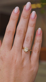 A video of an  Antique-inspired, solitaire engagement ring being worn on a wedding finger.  Rotated slowly to showcase the pale yellow sapphire and yellow gold band. 