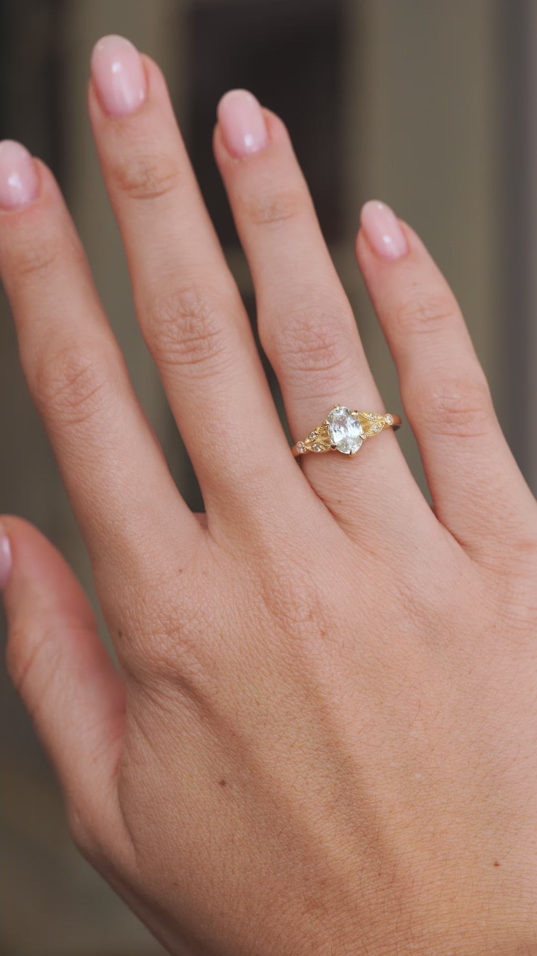 Video of the white sapphire engagement ring on the hand, capturing the oval gemstone’s brilliance and diamond sparkle.