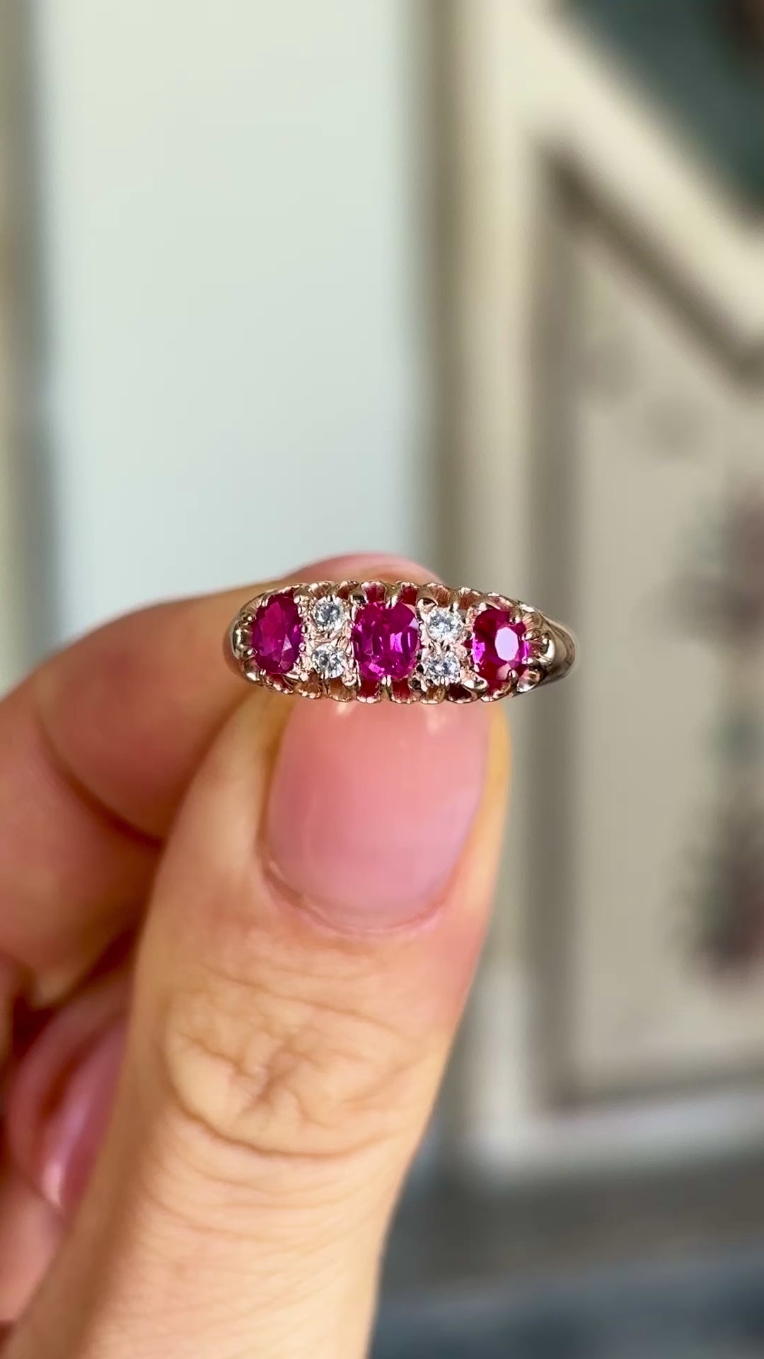 Antique, Victorian pinky-red ruby & diamond half-hoop ring held in fingers