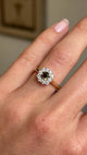 A close-up video of an Antique-inspired, Brown diamond cluster engagement ring, set with a central square-cut brown diamond surrounded by a halo of round brilliant-cut diamonds, worn on a wedding finger. 