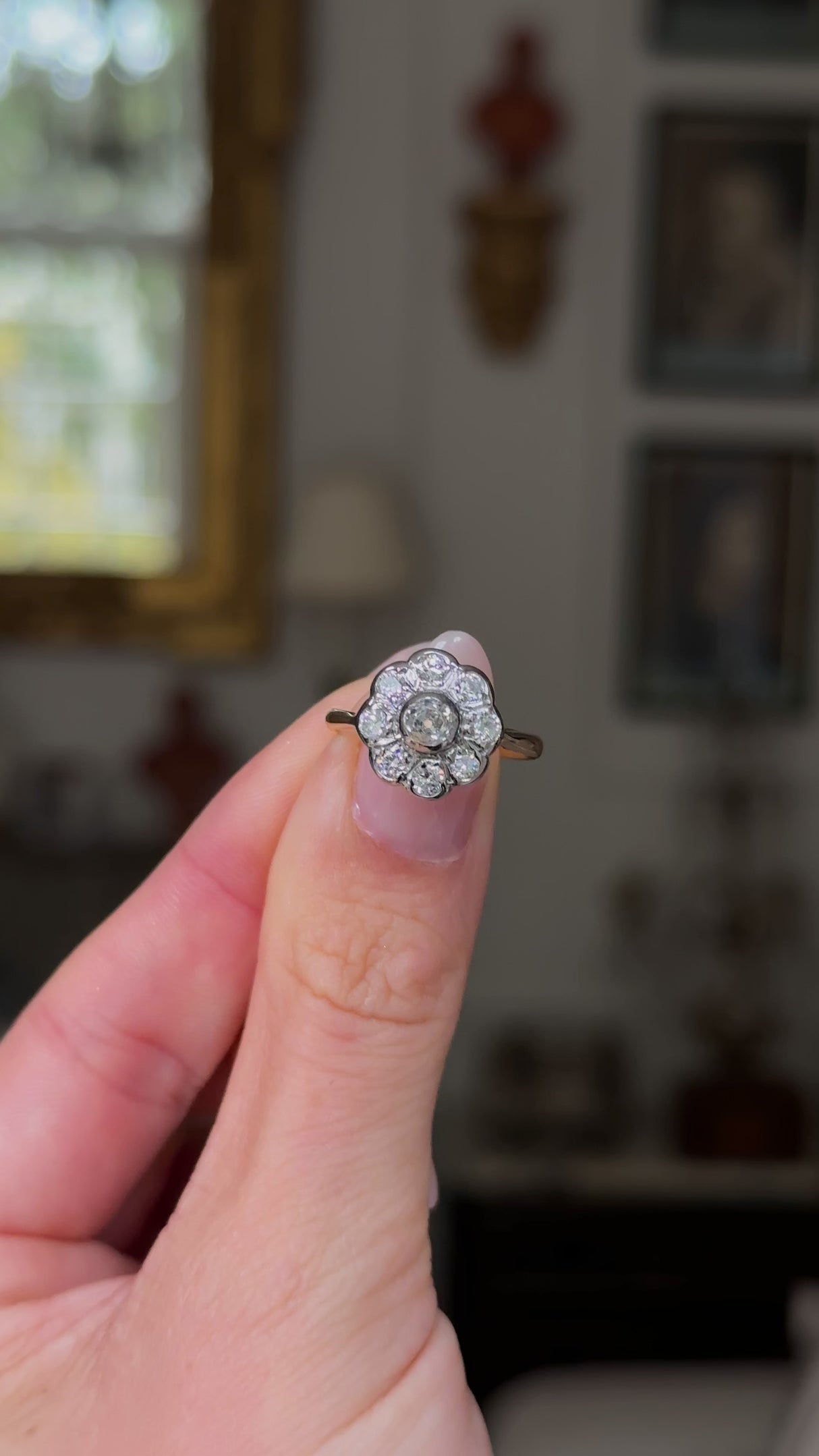 antique diamond daisy cluster engagement ring, held in fingers and rotated to provide perspective. 