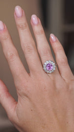 Video of the vintage cluster ring on the hand, capturing the vivid pink sapphire and surrounding diamond sparkle.