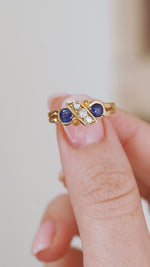 Video close-up on a fingertip highlighting the unusual diagonal setting and curled yellow gold flourishes of the Victorian design.