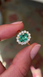 Antique-inspired emerald and diamond cluster ring in yellow gold, filmed on hand to highlight the oval-cut emerald centre stone, sparkling diamond surround and timeless vintage-inspired style.