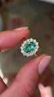 Antique-inspired emerald and diamond cluster ring in yellow gold, filmed on hand to highlight the oval-cut emerald centre stone, sparkling diamond surround and timeless vintage-inspired style.