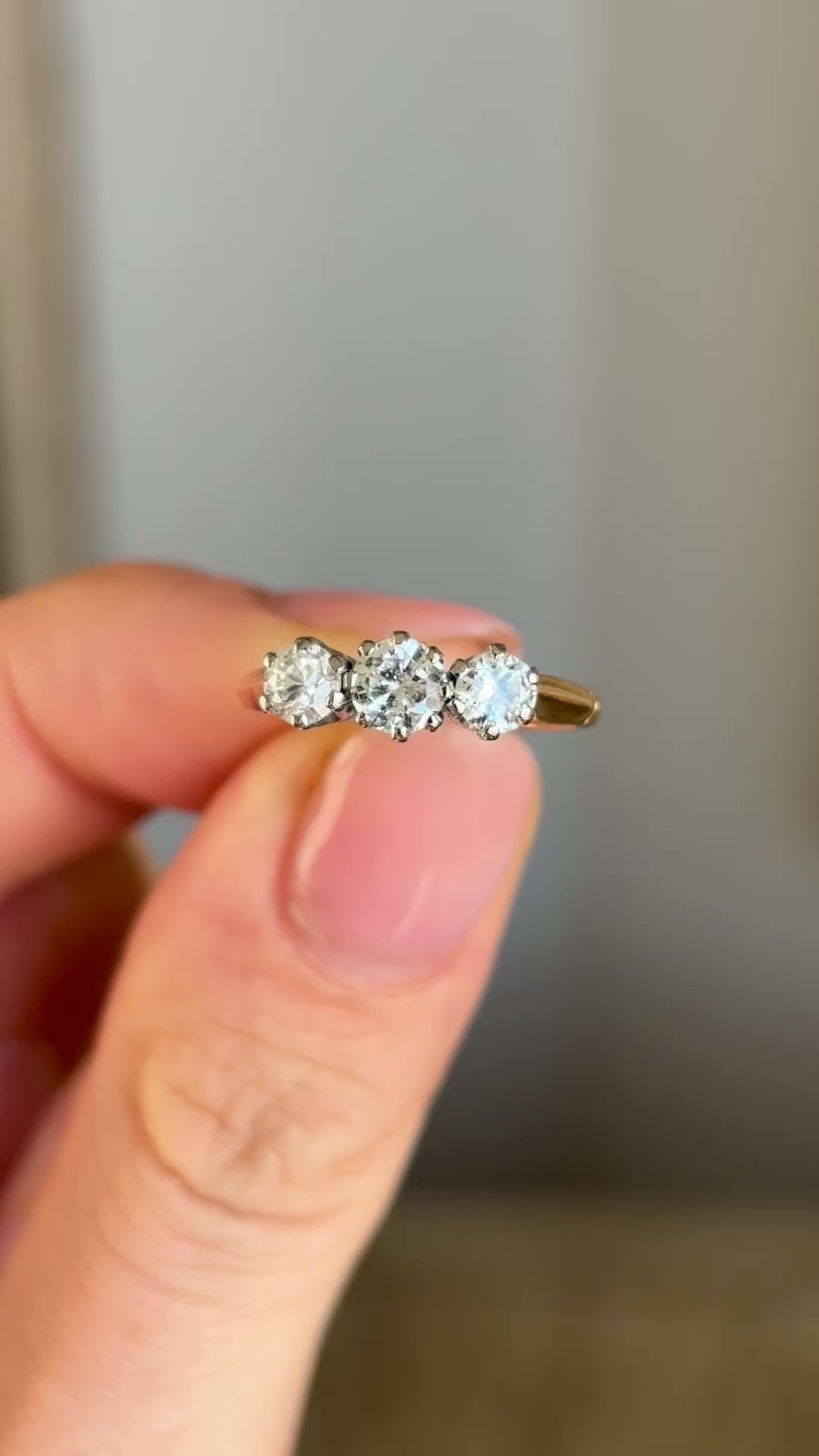 Vintage, 1970s three-stone diamond ring held in fingers.