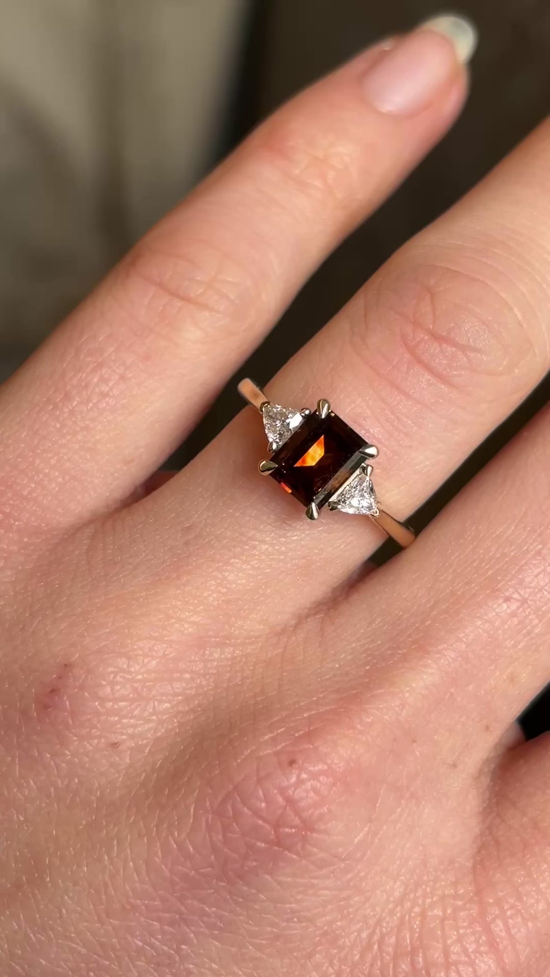 Brown diamond three-stone engagement ring in video on hand at a distance to show scale