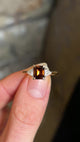 Brown diamond three-stone engagement ring in fingers and rotated to show details