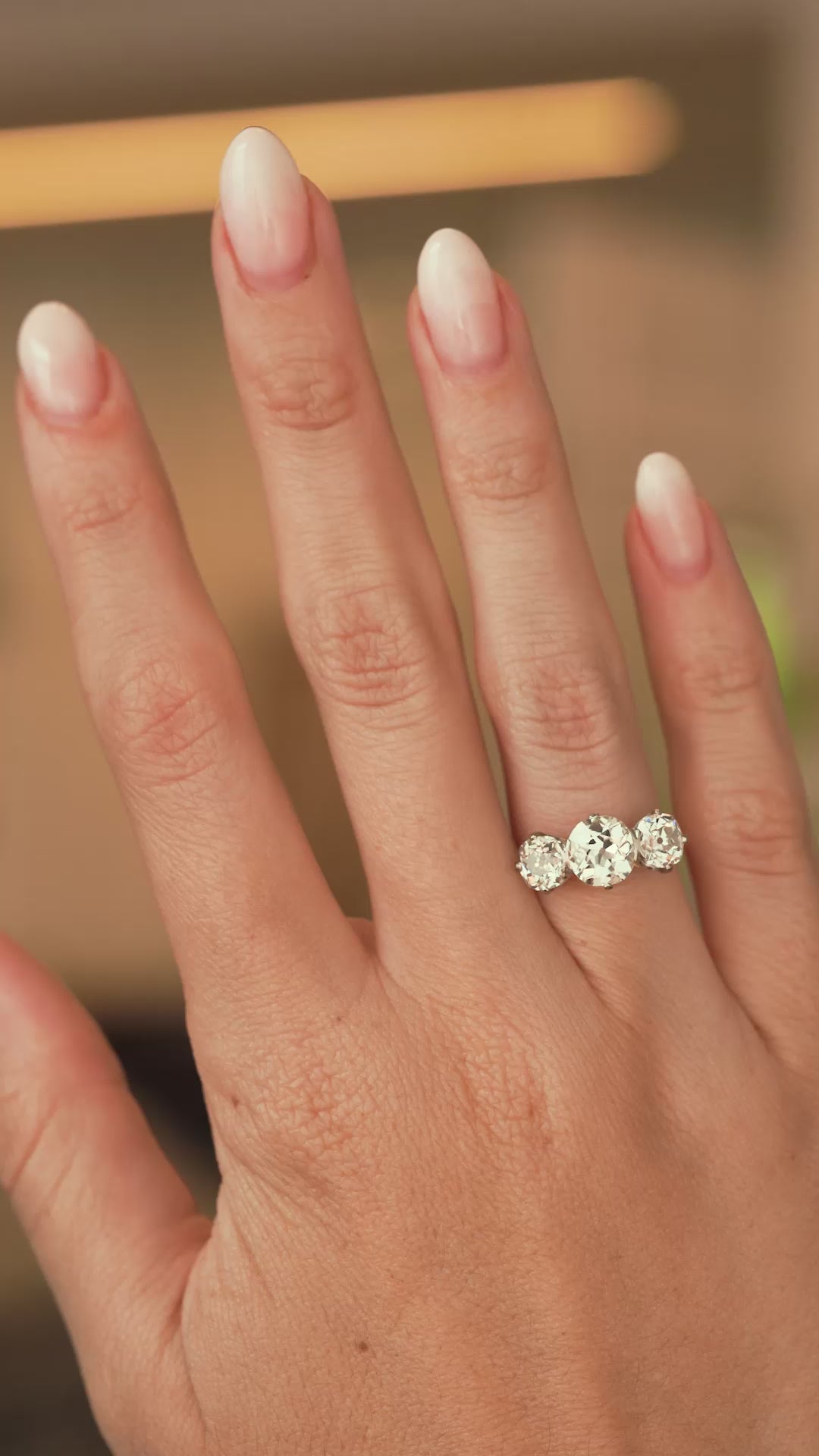 A video of a Antique, Edwardian old-cut diamond three-stone engagement ring and platinum being worn on an outstretched hand and slowly turned to show off the proportions.