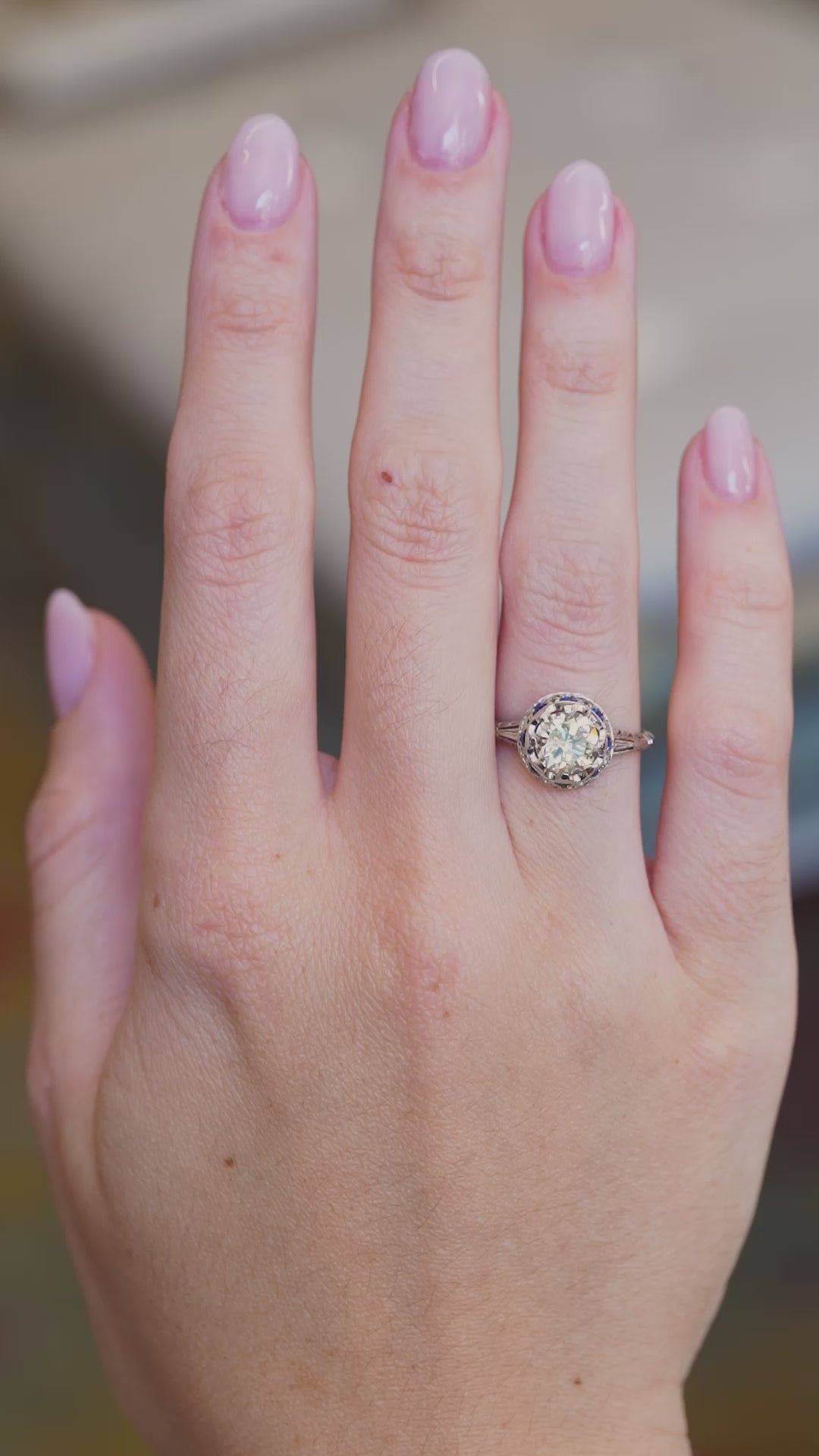 Art Deco diamond and sapphire cluster ring worn on hand showing diamond sparkle and sapphire accents in movement.