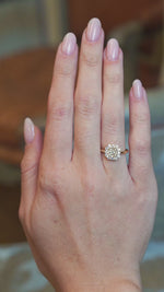 Diamond cluster engagement ring worn on hand showing subtle movements.