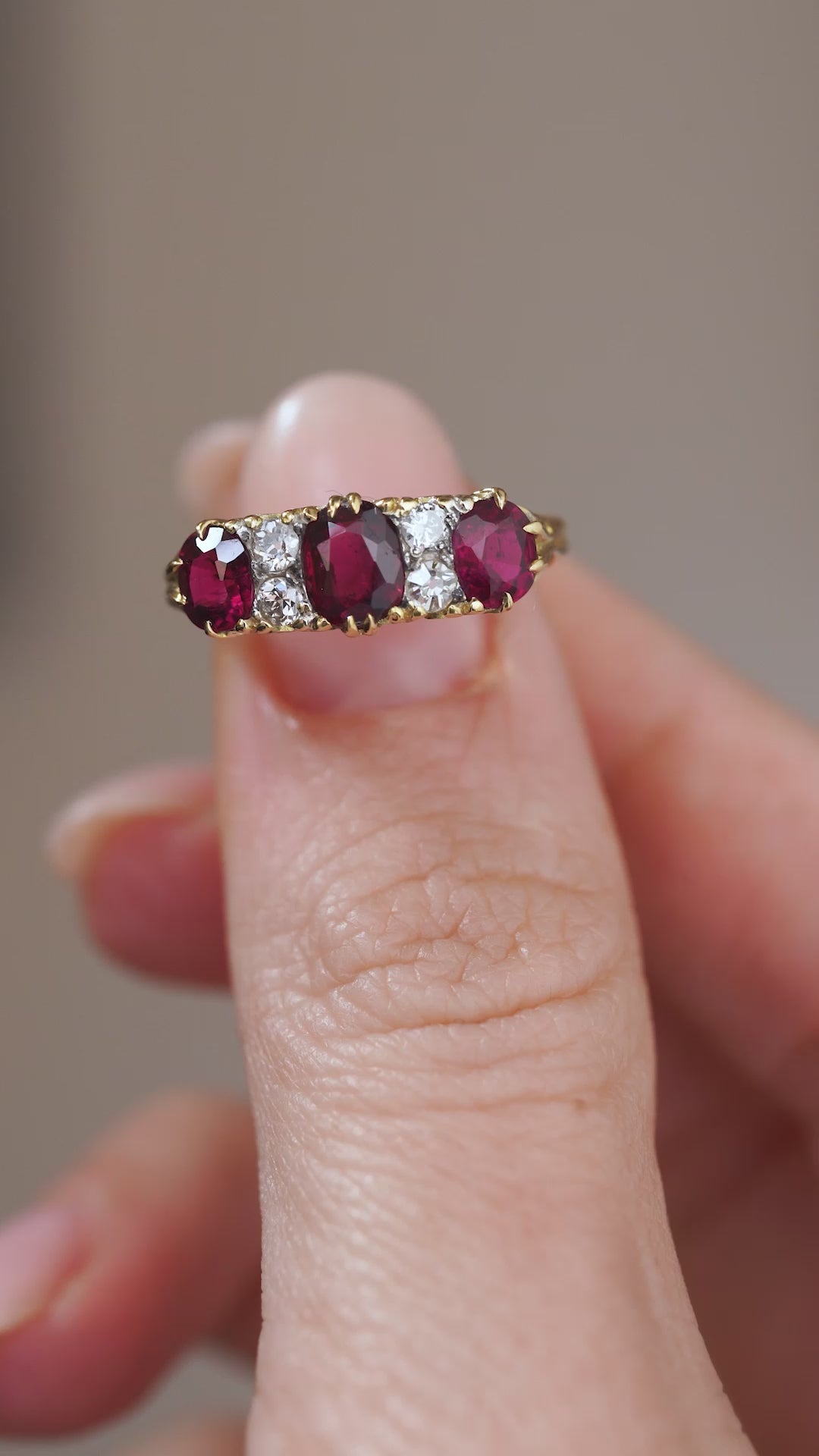 Video presenting the antique three-stone ring balanced on a fingertip for a clear view of its ruby and diamond arrangement.
