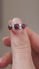 Video presenting the antique three-stone ring balanced on a fingertip for a clear view of its ruby and diamond arrangement.