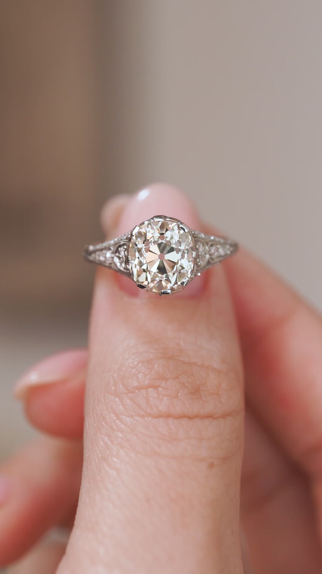 Video close-up of the Edwardian solitaire balanced on a fingertip, showing its detailed setting and broad-faceted diamond.