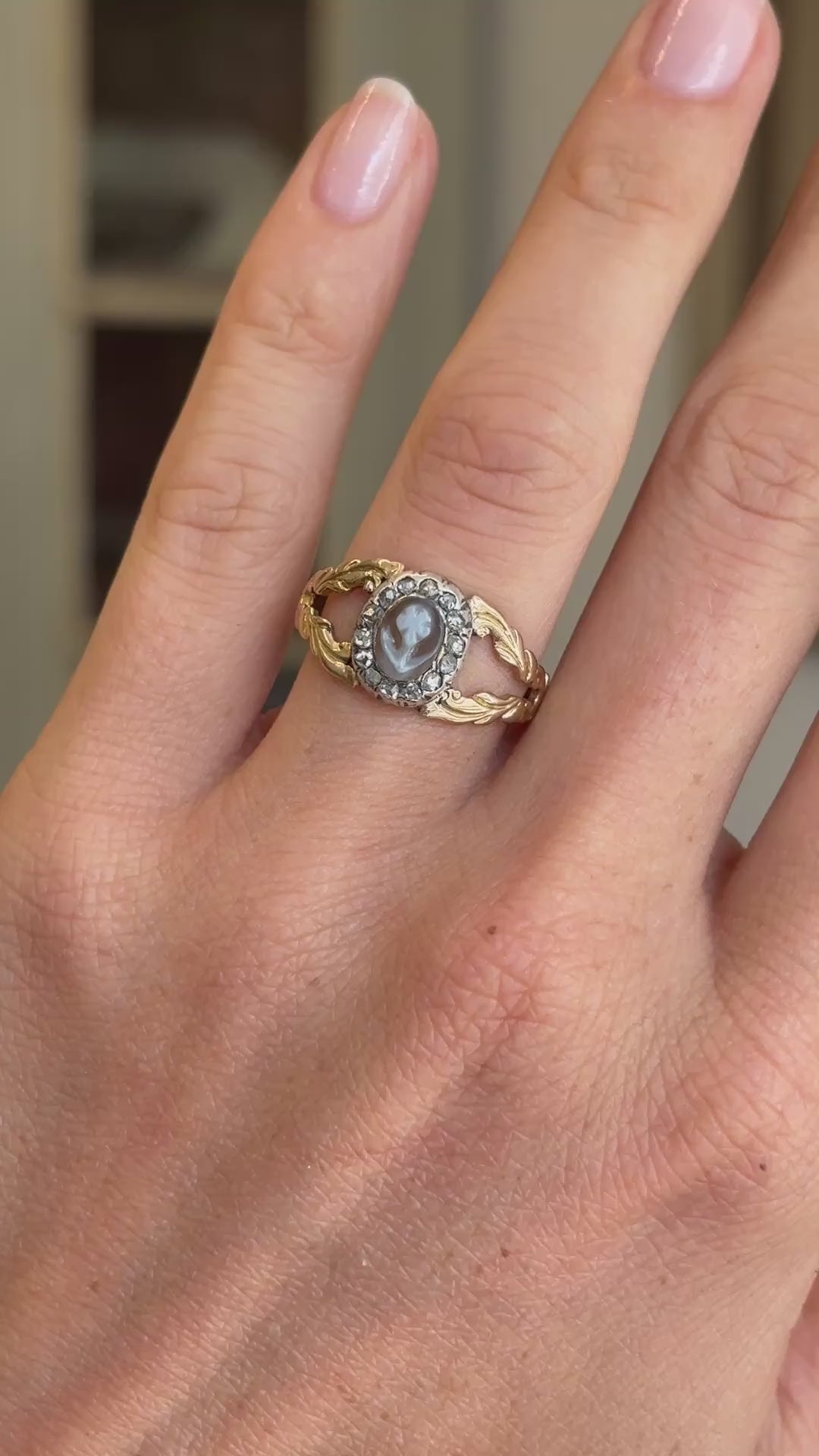 Antique Georgian forget-me-not cameo cluster ring featuring a hand-carved forget-me-not cameo in a decorative cluster setting, displayed on a hand.