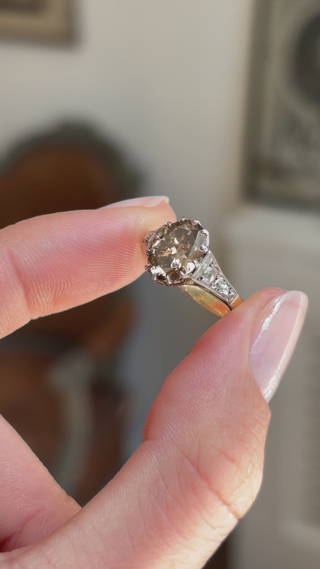 Antique-inspired hazelnut-brown diamond and rose-cut diamond engagement ring featuring a hazelnut-brown diamond centre stone with rose-cut diamond accents, held by hand for detailed viewing.
