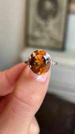 Close up video of an antique citrine cocktail ring from the 1930s Art Deco era, slowly rotated between two fingers to display all angles of the ring