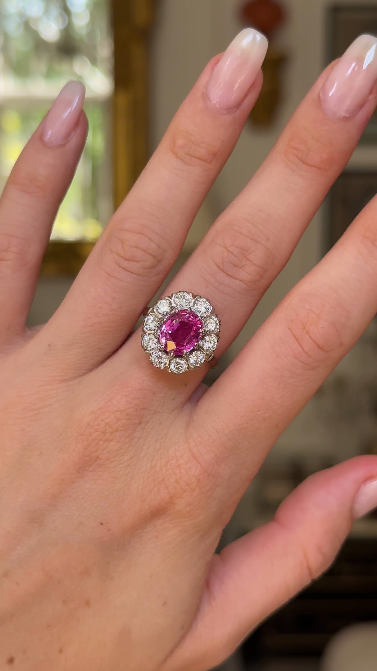 Pink sapphire and diamond cluster ring worn on hand and moved around to give perspective.