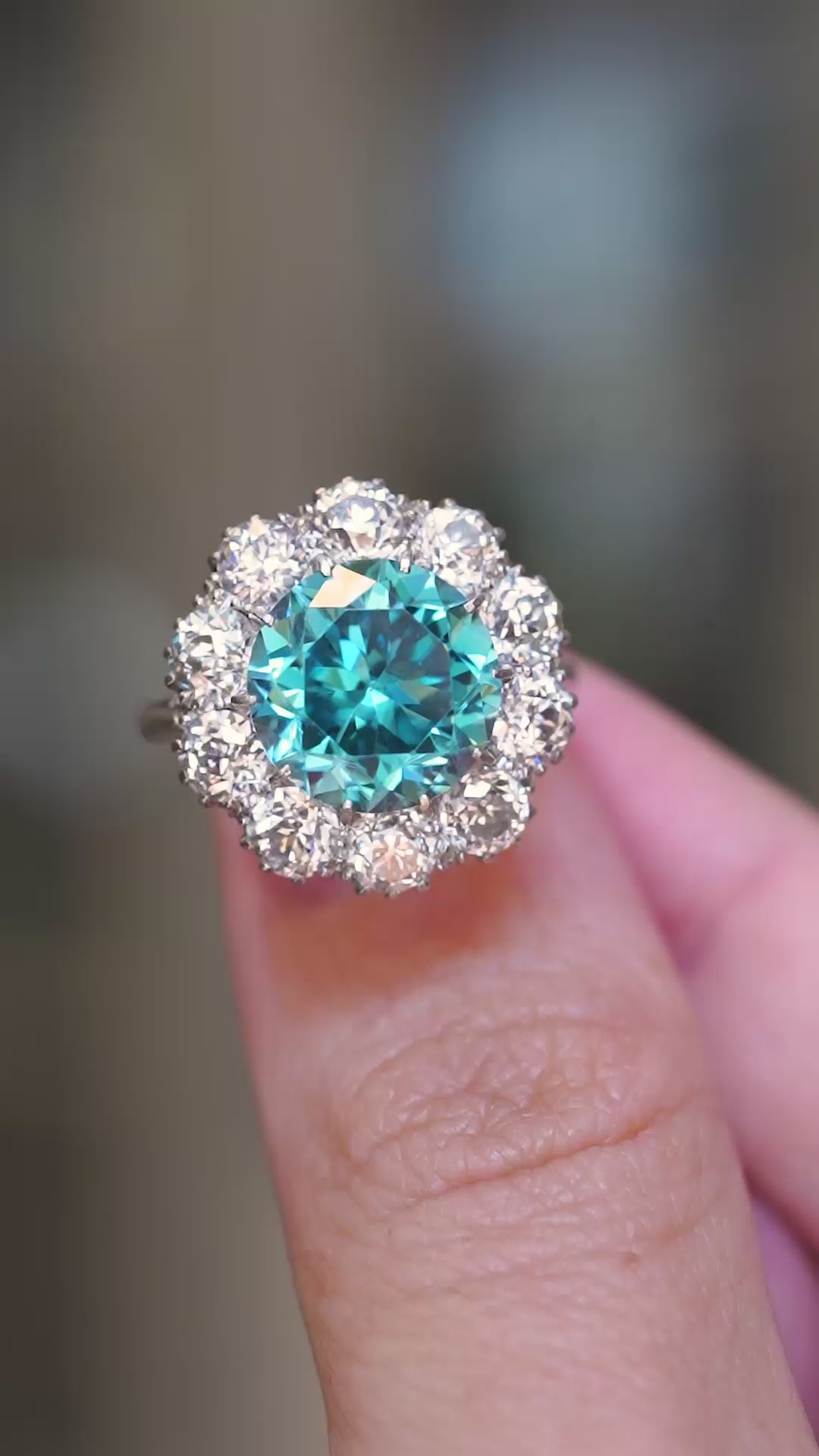 A close-up video showing an antique Edwardian blue zircon and diamond cluster cocktail ring held between fingers.