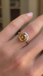 Video of an Antique-inspired, orange zircon solitaire ring in yellow gold worn on a wedding finger.