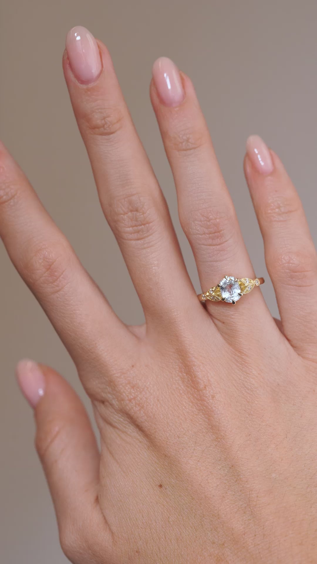 A video of the white sapphire and diamond ring worn on a finger, capturing the gemstone's sparkle and intricate vintage-inspired design.