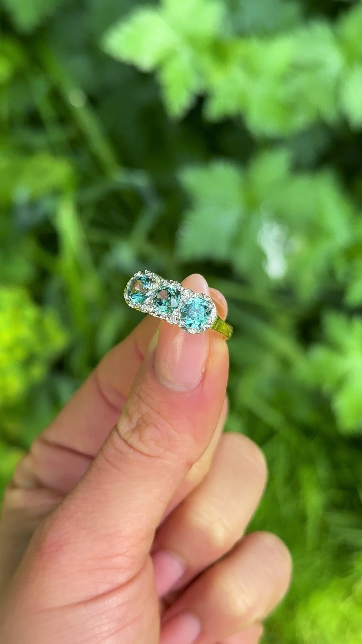 1930s Zircon and Diamond Three Stone Cluster Ring, 18ct Yellow Gold & Platinum held in fingers.