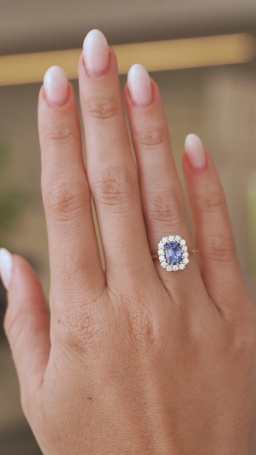 Video of an antique-inspired blue sapphire and diamond halo engagement ring worn on the hand, capturing its sparkle and proportions.