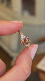 A Vintage-inspired, orange sapphire & diamond trefoil engagement ring in yellow gold shown in video between fingers.